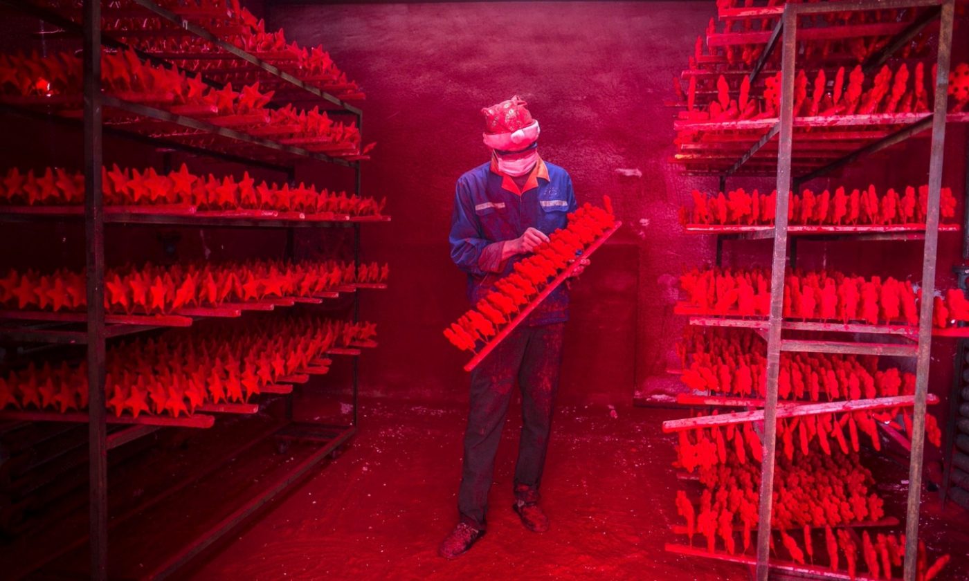 Dos hombre producen cerca de 5.000 gorros de Papá Noel cada día por unos 385 euros al mes. Foto: China Daily/Reuters