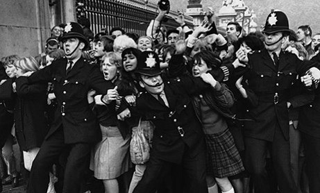 Imagen de una masa de fans de los Beatles intentando ser contenida por la policía [Foto vía 50añosdebeatlemanía].