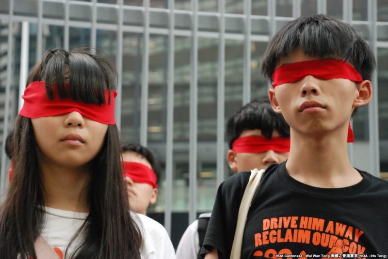 Joshua Wong, otro de los líderes estudiantiles, protesta simbólicamente contra el régimen chino [Foto: Wikipedia]
